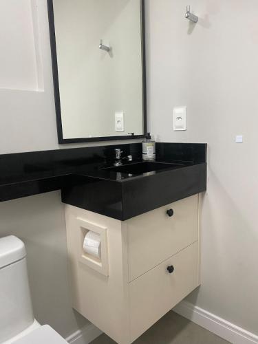 a bathroom with a sink and a mirror at LINDO LOFT 350m Vila Germânica in Blumenau