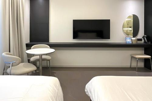 a room with two beds and a tv and two tables at 코브스테이 해운대 in Busan