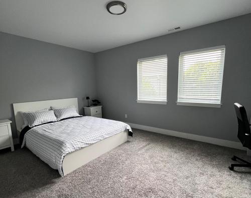 a bedroom with a white bed and two windows at Cozy and stylish 3BR house in Tacoma
