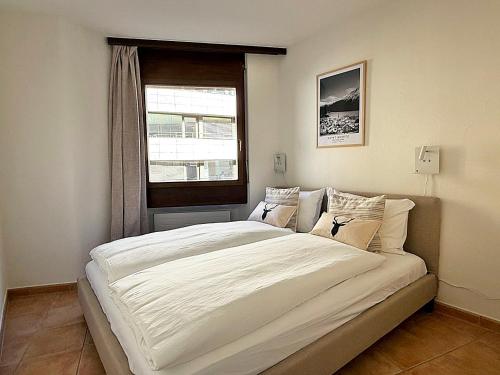 a large white bed in a room with a window at Zentrale Oase, Ski, Berge Spass, 45m2, für 2P - C8 in St. Moritz