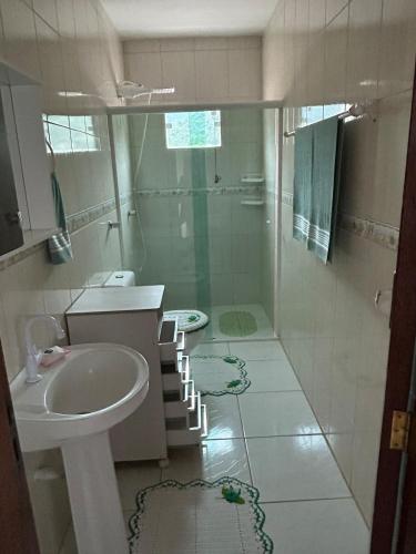 Un baño blanco con lavabo y ducha. en Residencial lara 101, en Itapema