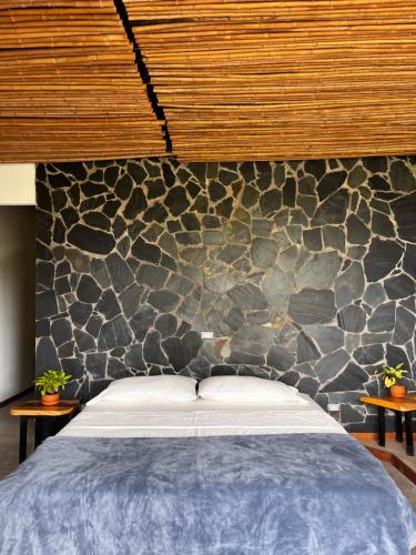 PapagallerosNatural Luxury Birding Lodge的一间卧室，配有一张大床和一堵石墙