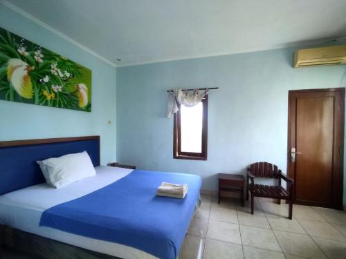 a bedroom with a bed and a chair and a window at Citepus Indah Hotel in Citepus