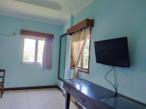 un soggiorno con TV a schermo piatto a parete di Citepus Indah Hotel a Citepus