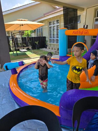two children are playing in an inflatable pool at Homestay BAYT AL - JAZMY in Kuantan