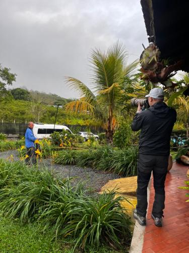 a man taking a picture of a garden with a camera at Natural Luxury Birding Lodge - Premium Birdwatching near Cali in Papagalleros