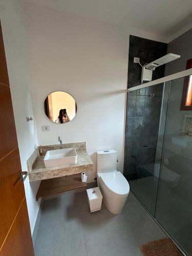 a bathroom with a toilet and a sink and a shower at Casa térrea moderna em condomínio in Bertioga