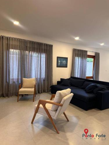 a living room with a couch and a chair at Casa térrea moderna em condomínio in Bertioga