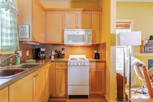 a kitchen with wooden cabinets and a white stove top oven at Rustic Cabin on 28-Acre Property in the Foothills of the Blue Ridge Mountains in Elkin