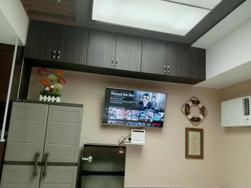 eine Küche mit einem Fernseher an der Wand und einem Kühlschrank in der Unterkunft Cozy Manila Condo Retreat with Shared Pool in Manila