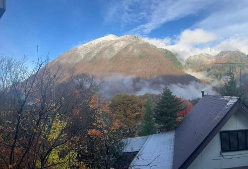 a mountain in the distance with a house and trees at 山の湯 in Wada