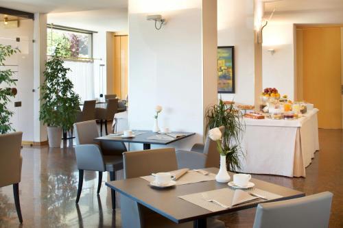 ベルガモにあるスターホテル クリスタッロ パレスのテーブルと椅子とカウンターのあるレストラン