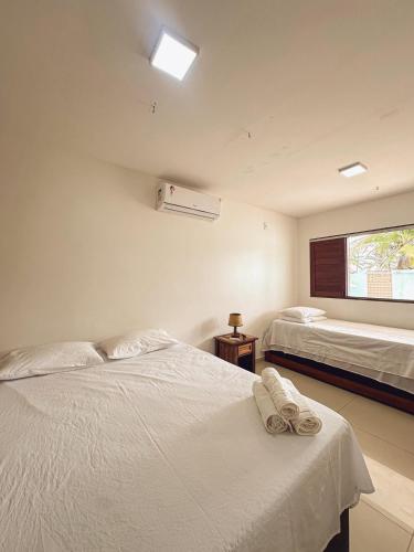 a bedroom with two beds and a window at Encanto à Beira-Mar com piscina no Pontal de Coruripe in Coruripe