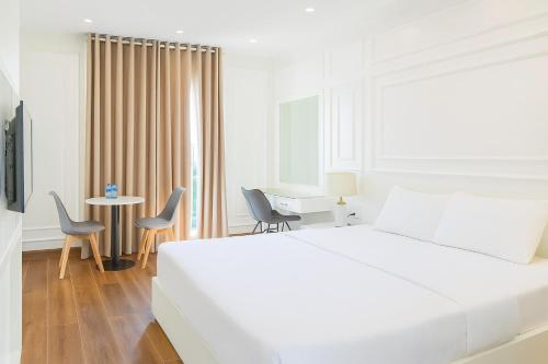 a white bedroom with a bed and a table and chairs at Gia Hưng Khang Hometel in Ha Long