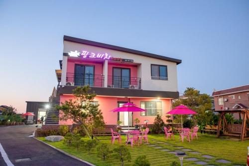 a building with pink chairs and umbrellas in front of it at Hajodae Pink Beach Pension in Yangyang