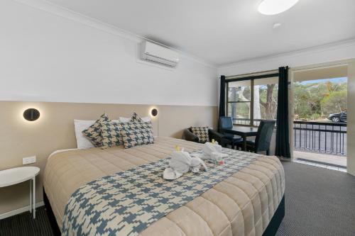 a bedroom with a bed with two stuffed animals on it at Kandos Fairways Motel in Kandos