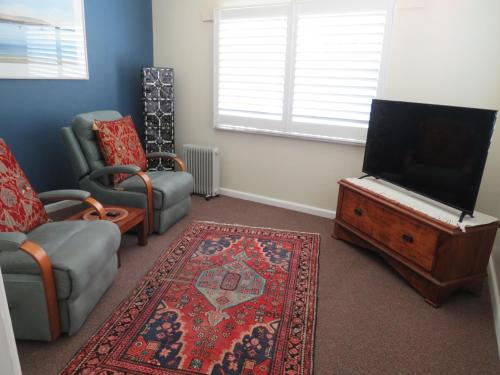 a living room with a tv and a couch and a chair at Lakes Entrance Waterfront Cottages with King Beds in Lakes Entrance