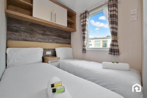 twee bedden in een kleine kamer met een raam bij Vacant Nests The Gullane Seton Sands in Port Seton