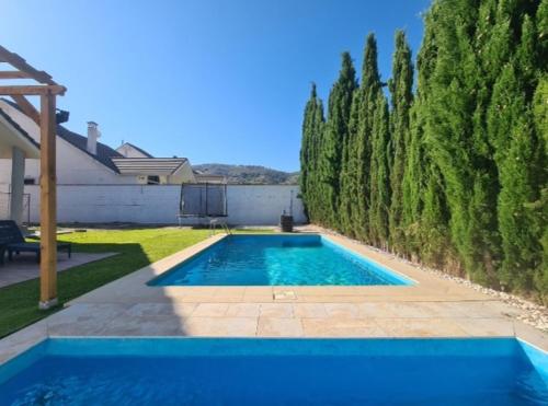 ein blauer Pool in einem Garten mit Bäumen in der Unterkunft Chalet con Piscina de,3 hab in Dílar