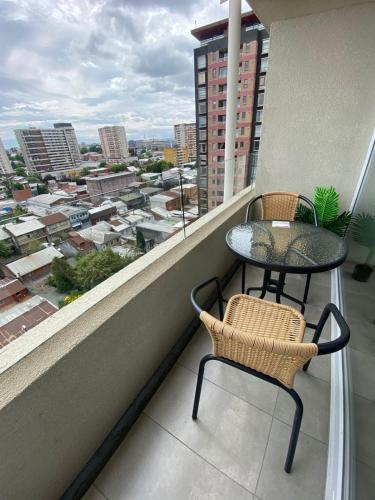 a balcony with a table and chairs and a view of a city at Apart Liucura Edificio Belmonte Temuco in Temuco