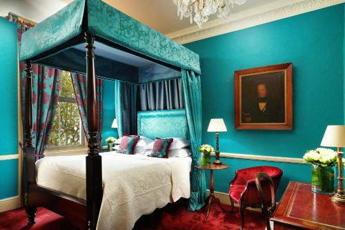 a bedroom with a canopy bed and blue walls at The Gore London - Starhotels Collezione in London