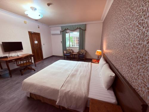 1 dormitorio con 1 cama grande, escritorio y TV en 巨地花園莊園, en Xinshi