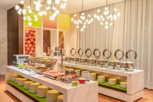 湛江湛江人民大道希尔顿欢朋酒店Hampton by Hilton Zhanjiang Renmin Avenue的餐厅的自助餐,包括盘子和食物