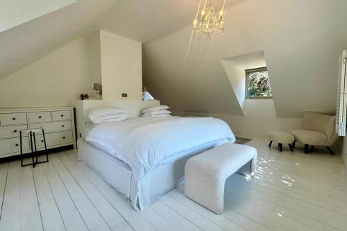 a white bedroom with a bed and a chair at Elegant Hampshire Countryside Stay in Petersfield