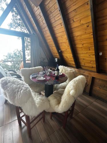 a dining room with a table and white chairs at A-Frame da Lagoa in Imaruí