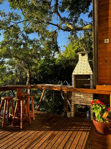a deck with a table and stools and a grill at A-Frame da Lagoa in Imaruí
