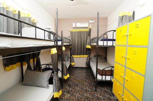a room with two bunk beds and yellow cabinets at Paradise A Social Hostel in Anjuna