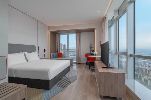 a bedroom with a bed and a desk with a television at Holiday Inn Express Chongqing Liangjiang Yufu by IHG in Chongqing