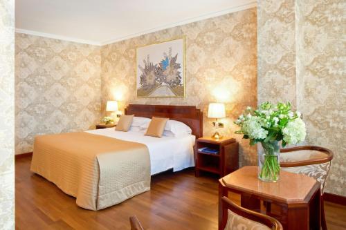 a bedroom with a bed and a vase of flowers on a table at Starhotels Du Parc in Parma