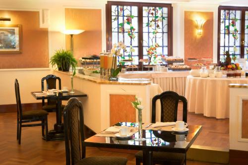 a restaurant with tables and chairs and stained glass windows at Starhotels Du Parc in Parma