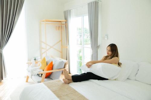 a woman sitting on a bed holding a pillow at Waveway bangsaen 1 in Ban Thai Don (2)