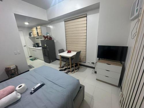 a bedroom with a bed and a table and a television at Condo near Santa Rosa-Nuvali-Enchanted in Pulong Cacawate