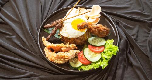 um prato de alimentos com um ovo frito e vegetais em Swiss-Belinn Seminyak em Seminyak