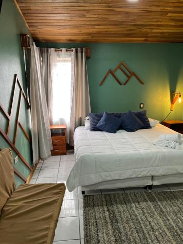 een slaapkamer met twee bedden en een groene muur bij Monteverde Guesthouse in Monteverde Costa Rica