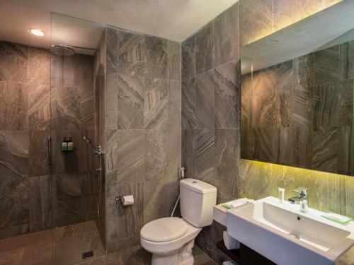 a bathroom with a toilet and a sink and a mirror at Laska Hotel Sukabumi in Sukabumi