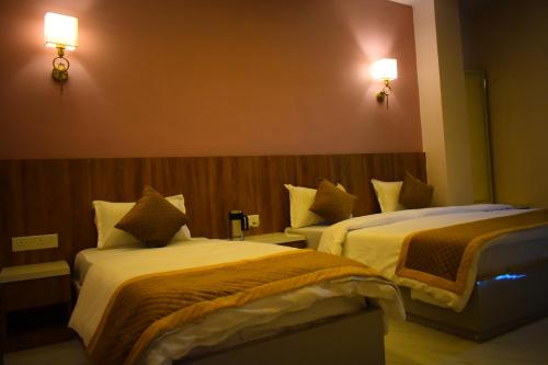 a hotel room with two beds and two lights on the wall at Radiant Sky Hotel in Kuchāman City