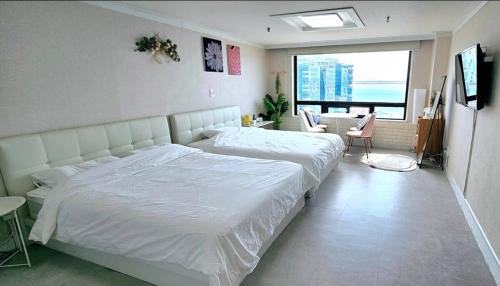 a bedroom with a large white bed and a desk at 스타샤인 in Busan