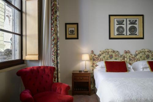 a bedroom with a bed and a red chair at Grand Hotel Continental Siena - Starhotels Collezione in Siena