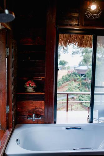 a bath tub in a room with a window at Mae Buya Coffee Farm Stay in Ban Huai Pong Nam Ron