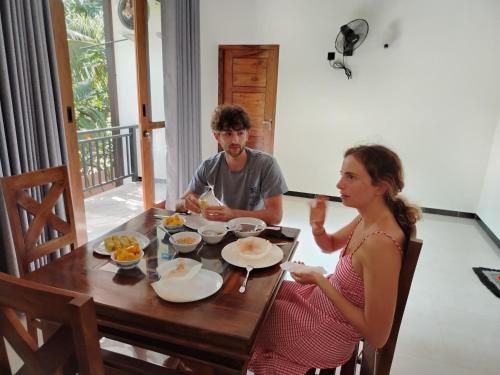 a man and a woman sitting at a table eating food at The Wasa Heaven in Hiriketiya
