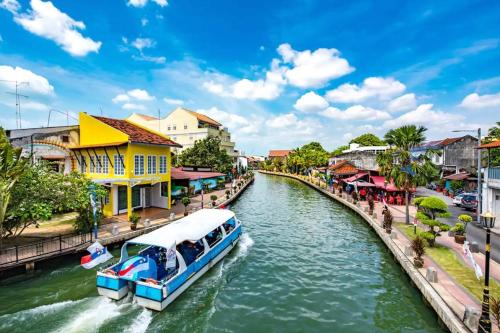 a boat traveling down a river in a city at Vintage Inn Jonker Walk Melaka in Melaka