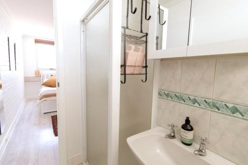 a white bathroom with a sink and a mirror at Heart of Freo - Ocean Views in Fremantle