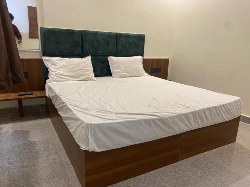 a bed with a green headboard and white sheets and pillows at Hotel O Riwaz Inn in Gwalior