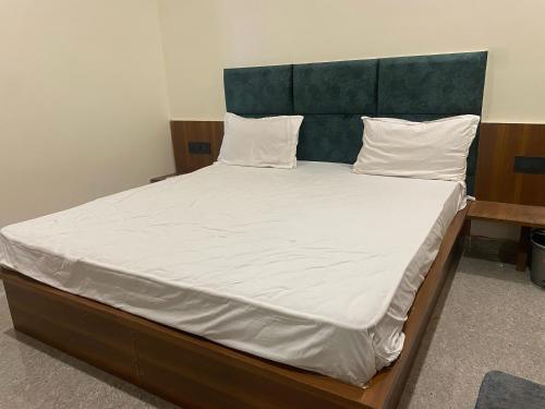 a large bed with white sheets and a green headboard at Hotel O Riwaz Inn in Gwalior