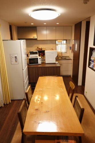 a kitchen with a wooden table and a refrigerator at Fukuoka Guest House Jikka in Fukuoka