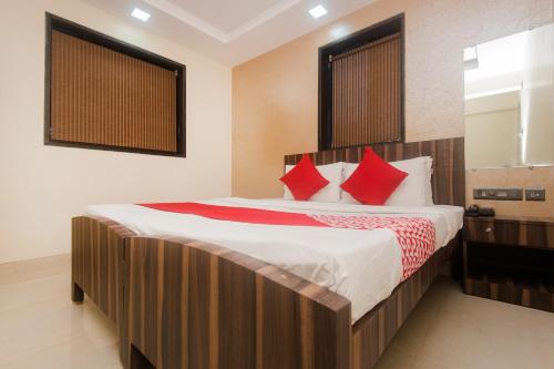 a bedroom with a large bed with red pillows at Hotel O Shalimar in Mumbai